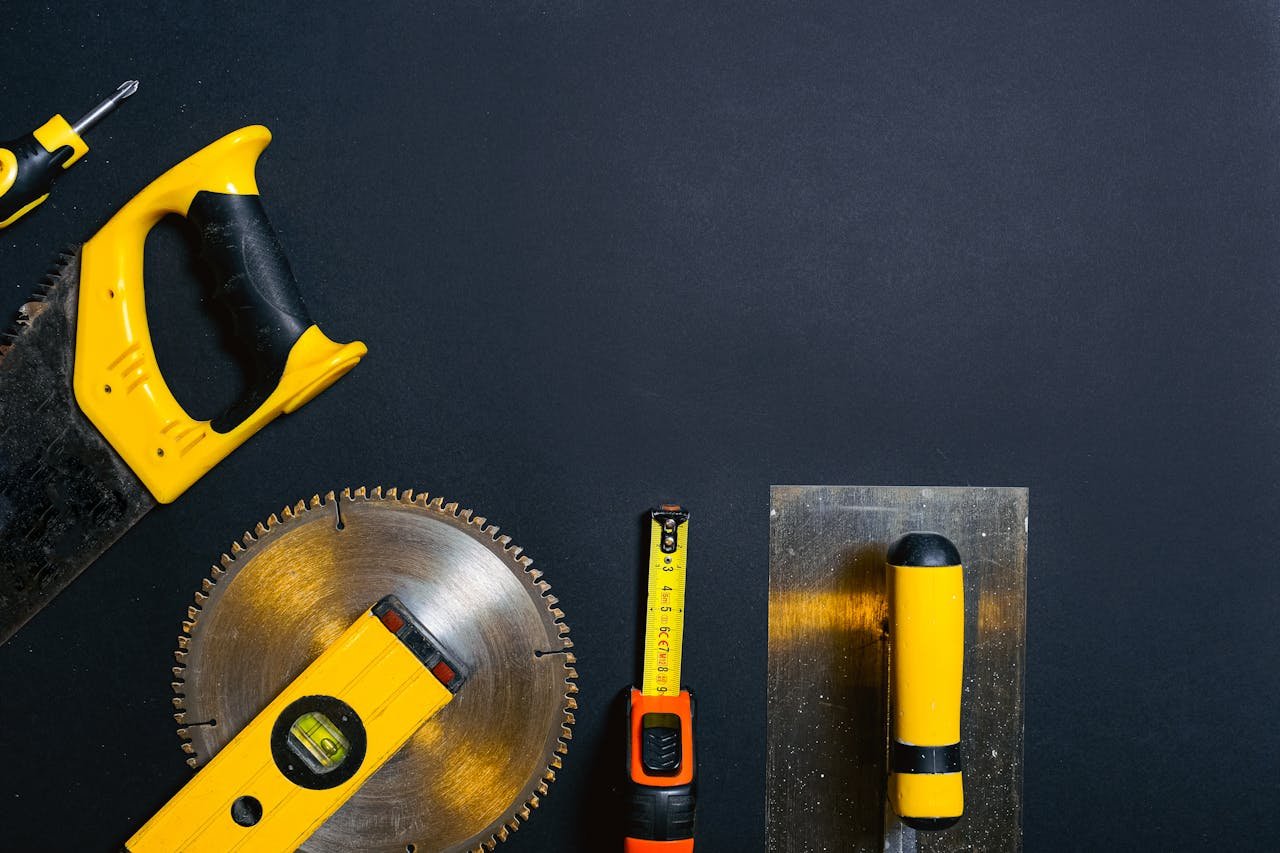 about-us Hand tools arranged on a black surface, featuring saws, levels, and a tape measure.